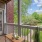 a deck with a table and chairs on it and a grass yard and trees in the background